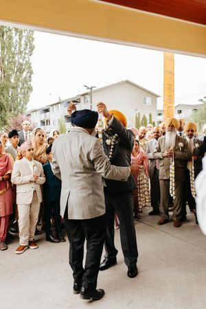 A crowd gathers to watch people dancing under a covered outdoor area during a celebration.