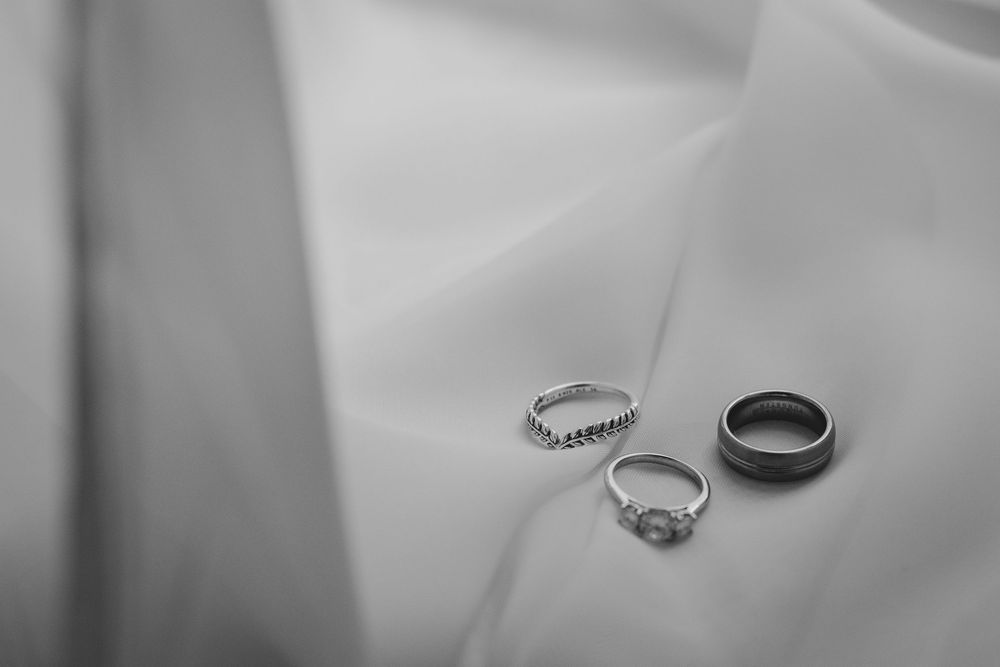 Three silver rings displayed on a white surface showing wedding and engagement ring details.