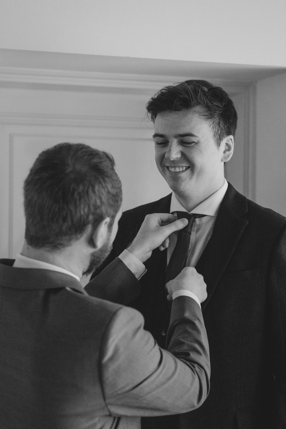 A heartwarming black and white moment between two people as one helps adjust the other's tie before a formal occasion.