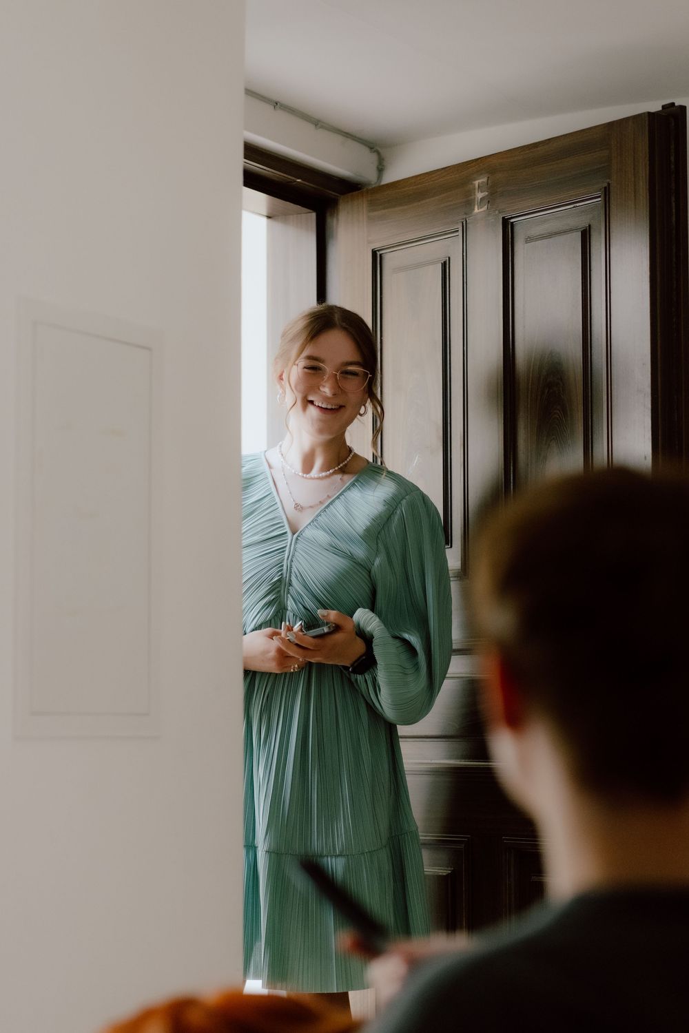A person in a mint green dress stands in a bright white room, creating a series of candid movements captured in sequence.