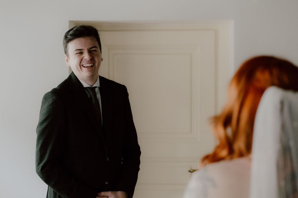 A couple shares laughter and joy during an intimate indoor photo session with natural lighting.