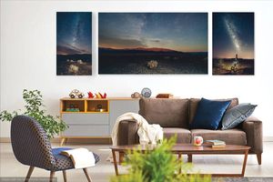 Modern living room interior with beautiful landscape photography triptych art above brown sofa and floating shelf decor.