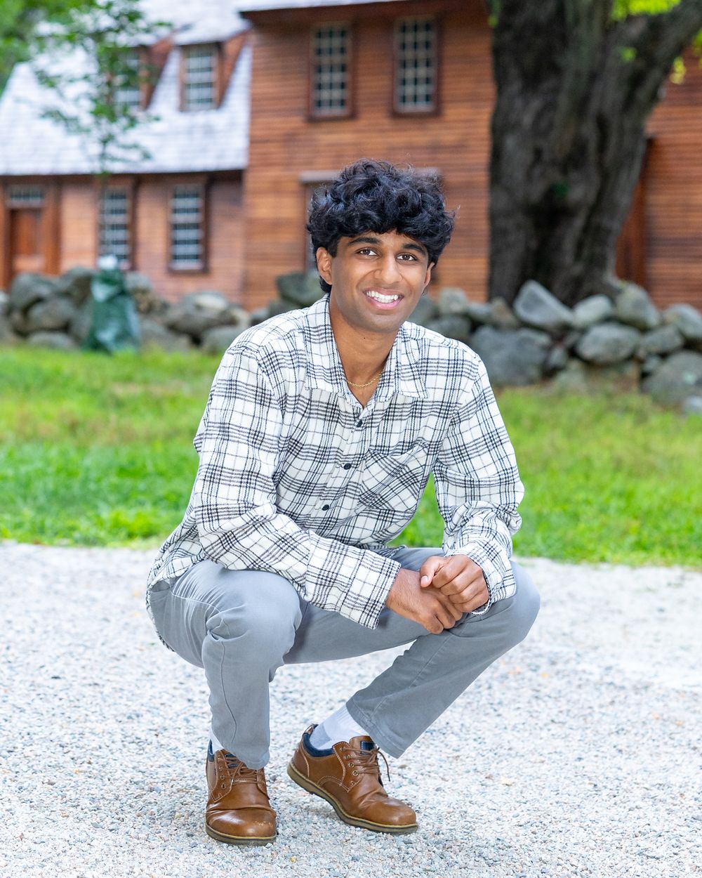 A high school senior poses on the grounds Hartwell Tavern in Lincoln, MA  in a yearbook photo session with Lisa West Photography. Concord
