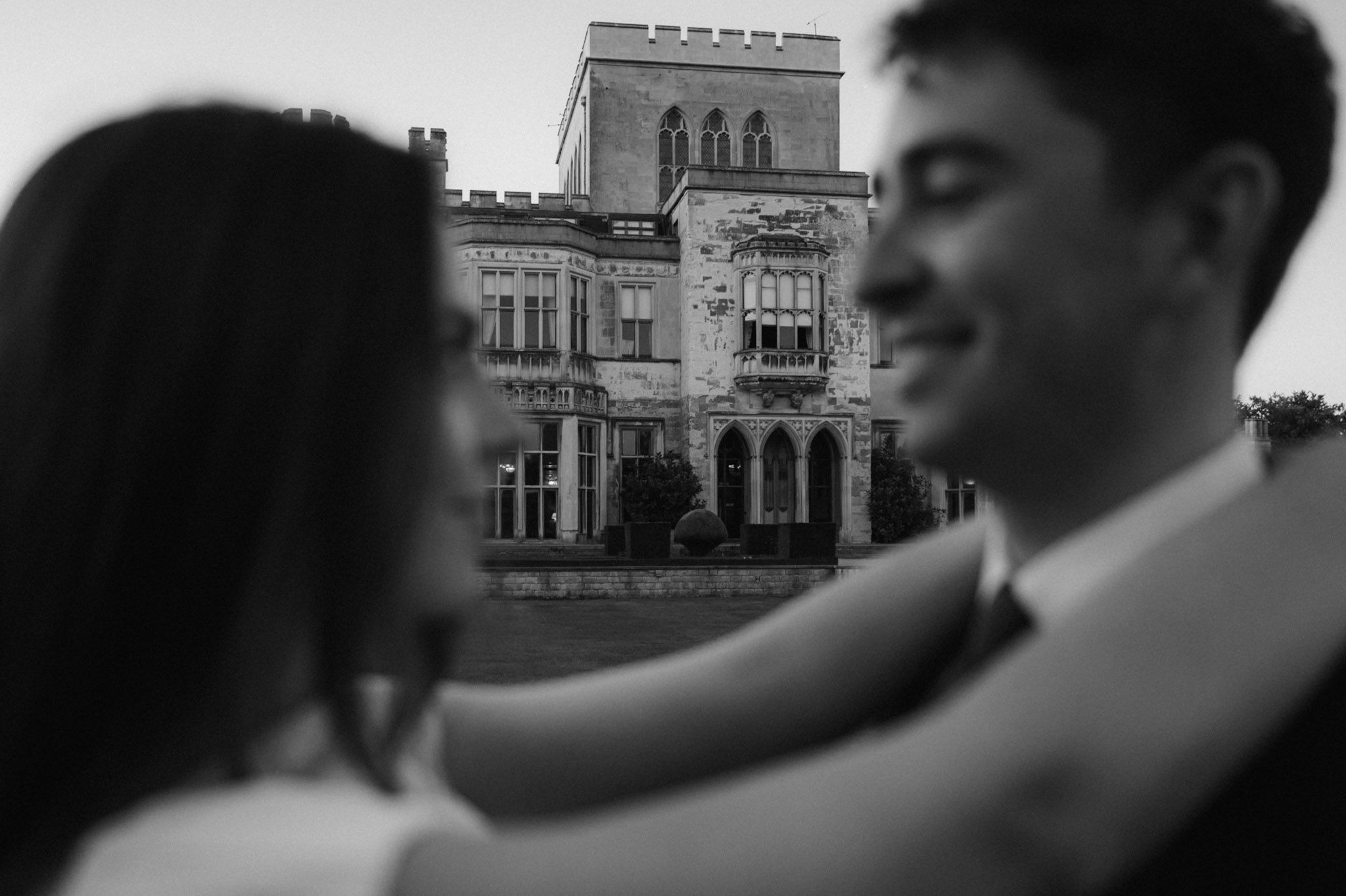 A romantic black and white portrait in front of a historic building.