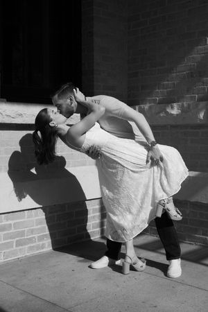 Dramatic black and white photos showing a romantic dip pose against a brick wall.