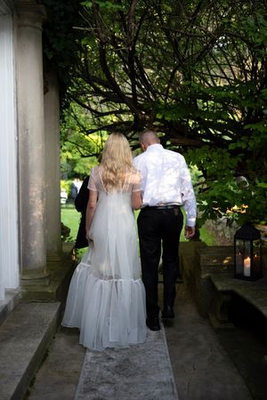 Wedding couple walking through a covered garden pathway.
