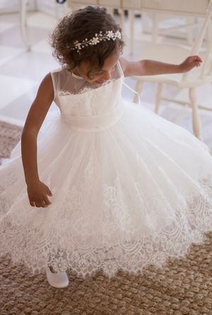 White lace dress with delicate details twirls on a beige carpeted floor.