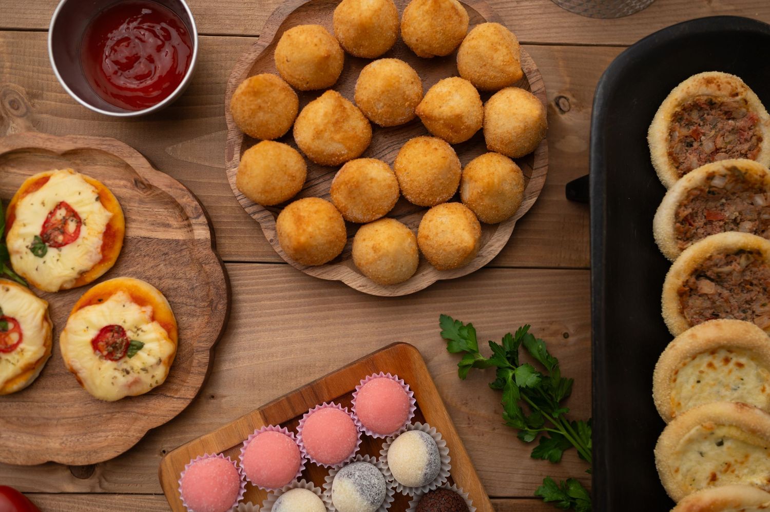 Overhead shot of various baked goods, sauces, and colorful Easter eggs on a wooden table.