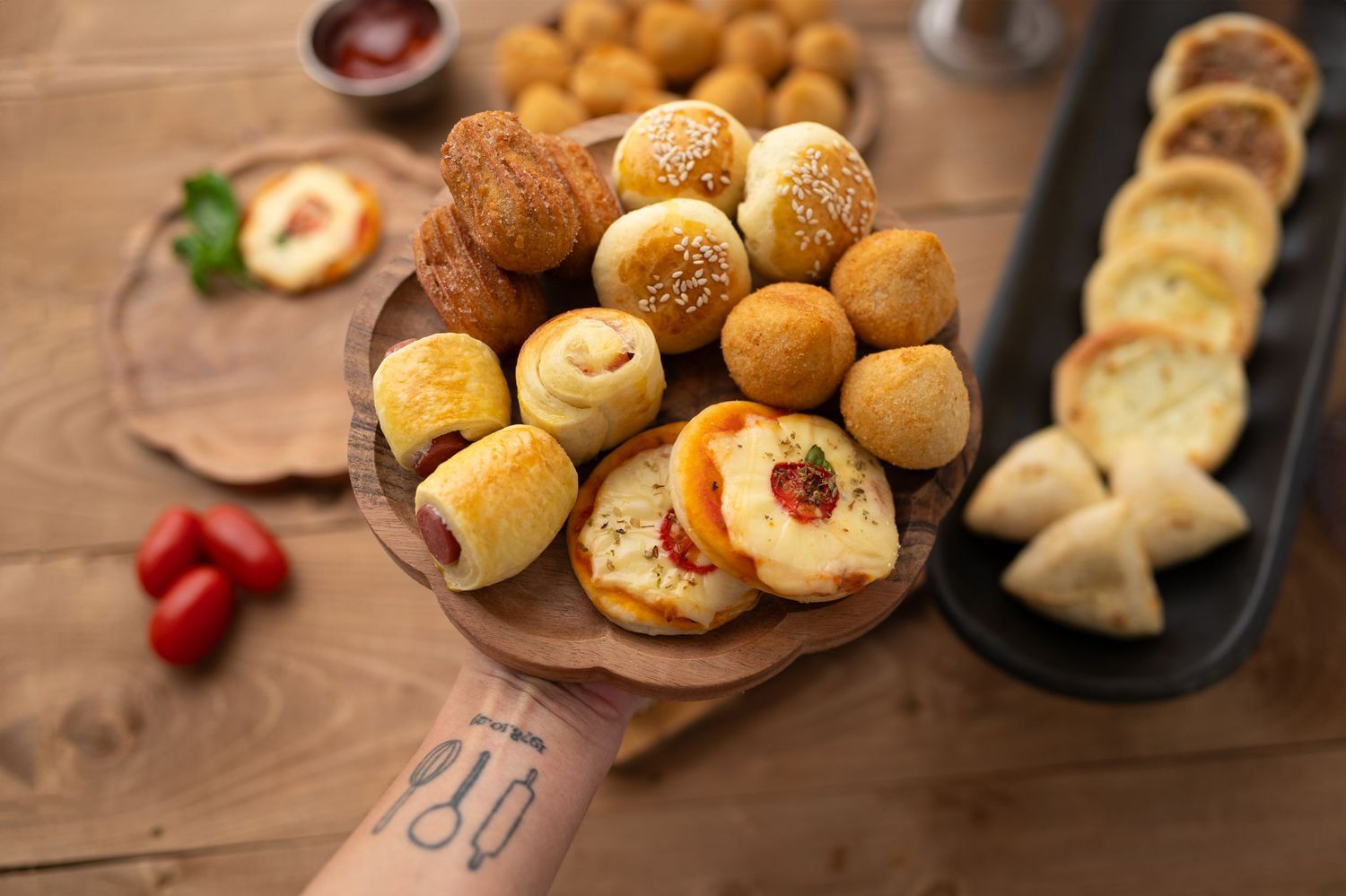 Assorted freshly baked rolls and pastries displayed on wooden serving boards with garnishes.