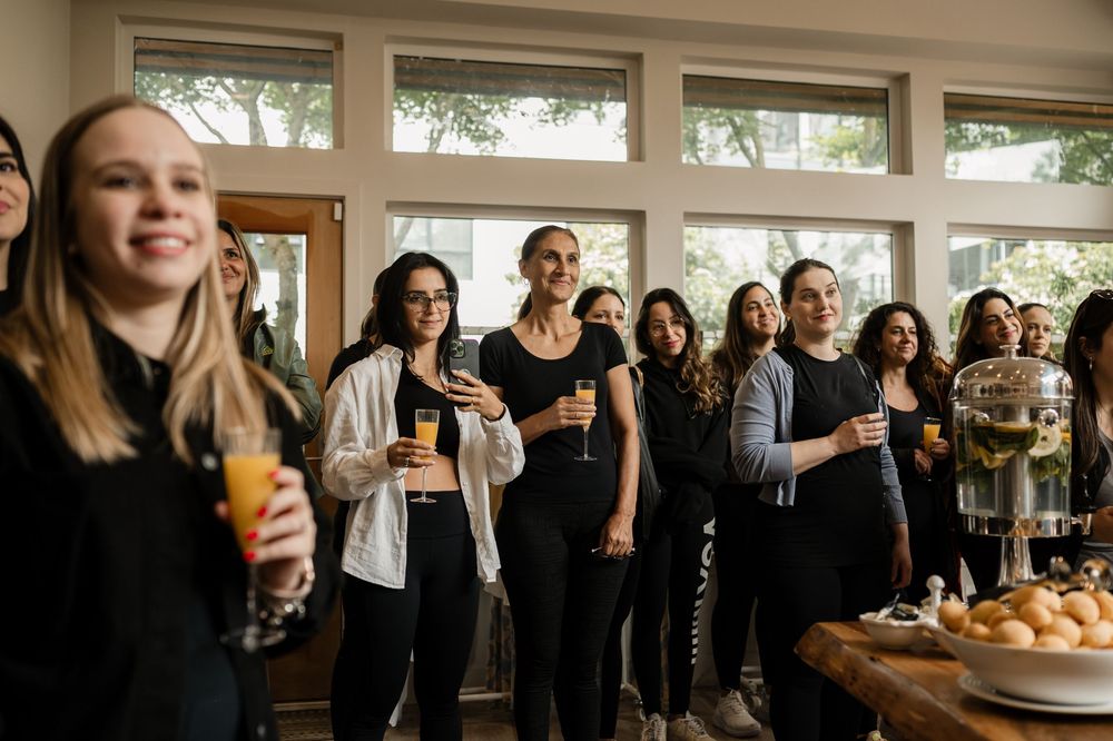People in black attire holding drinks while mingling at a social gathering.