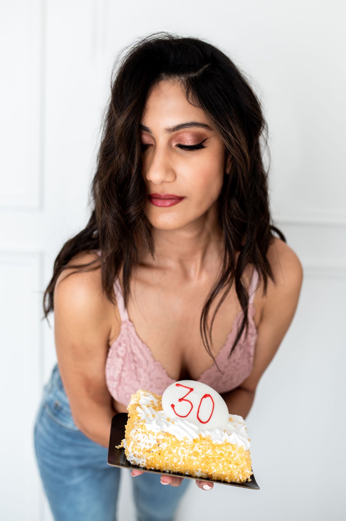 Birthday celebration scene with person holding slice of cake with number 30 candle.