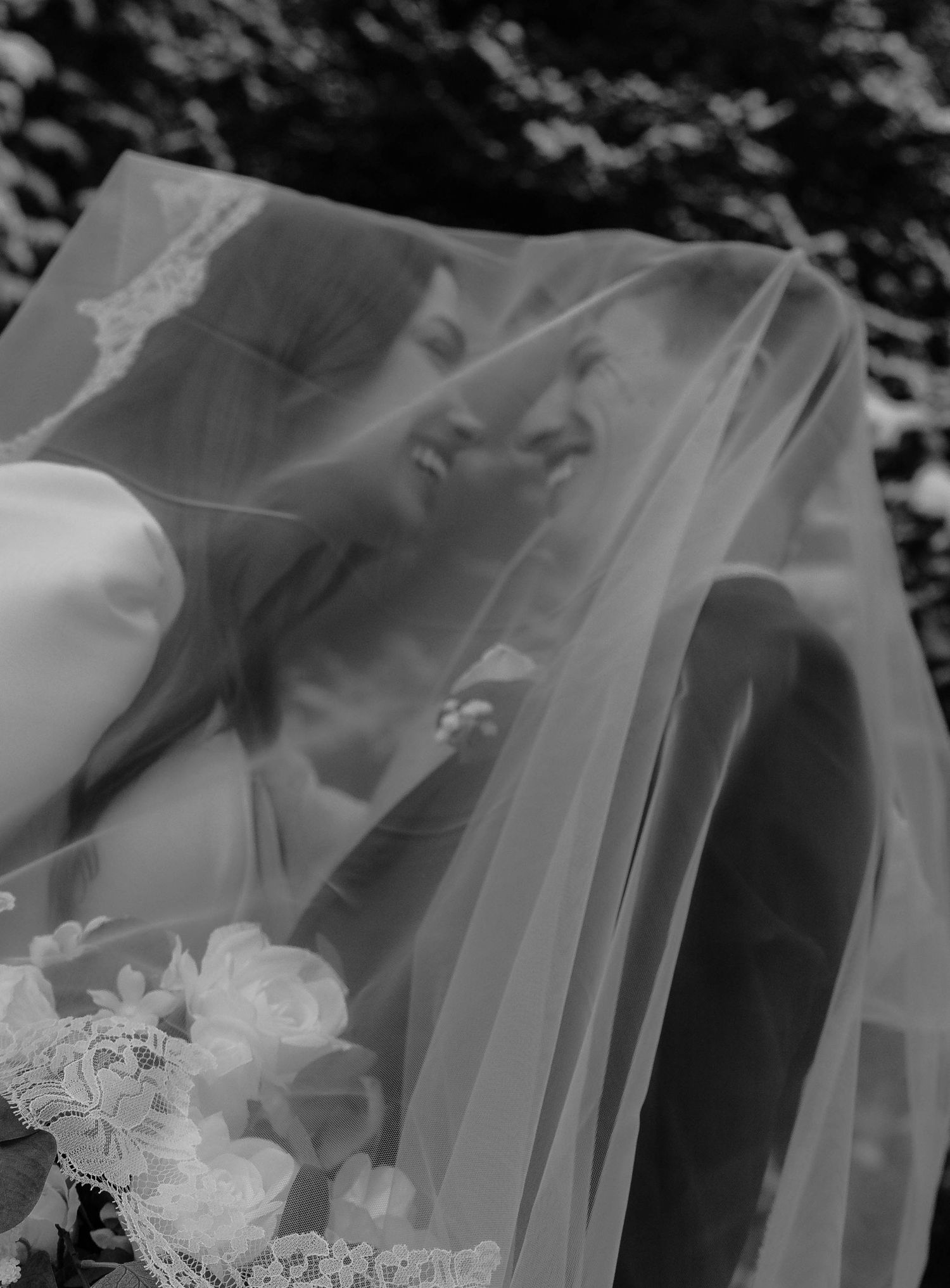 Close-up details of delicate white lace and tulle fabric from a wedding veil in black and white.
