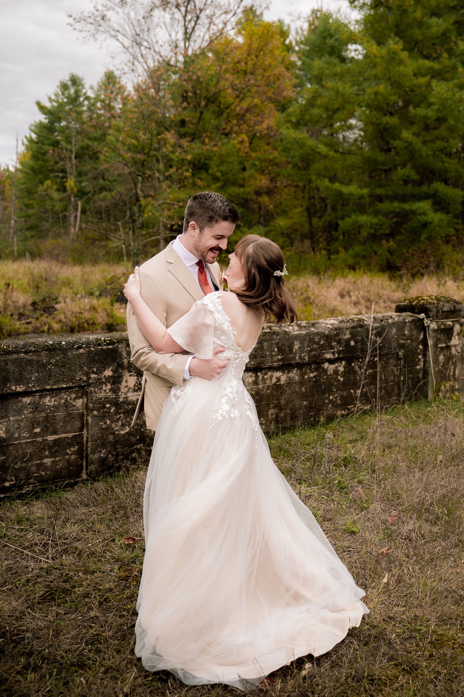 A romantic dance sequence between a couple in formal wedding attire amid an autumn outdoor setting with stone walls.
