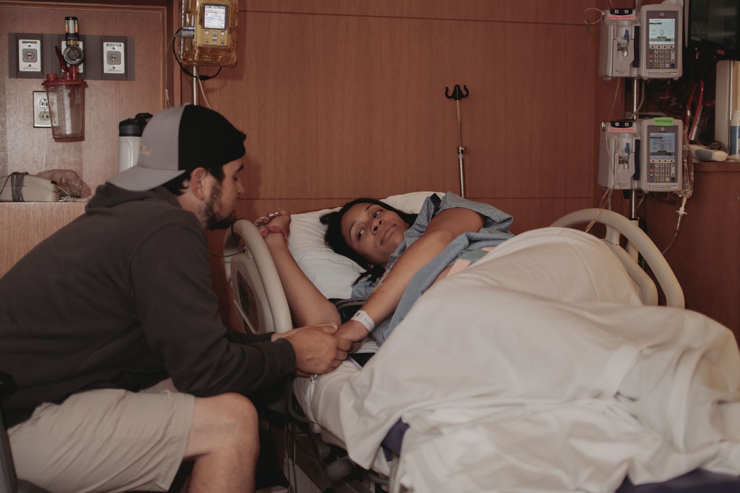 A tender moment in a hospital room as someone comforts a patient in bed.