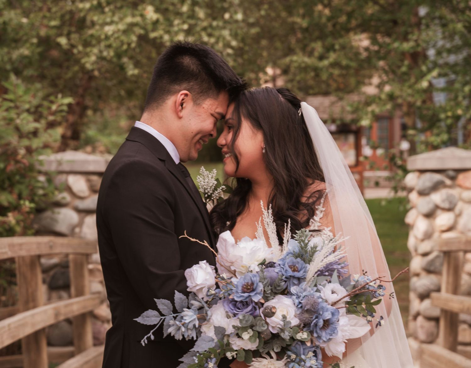A couple shares a romantic moment in a garden setting with purple and blue floral bouquet details.