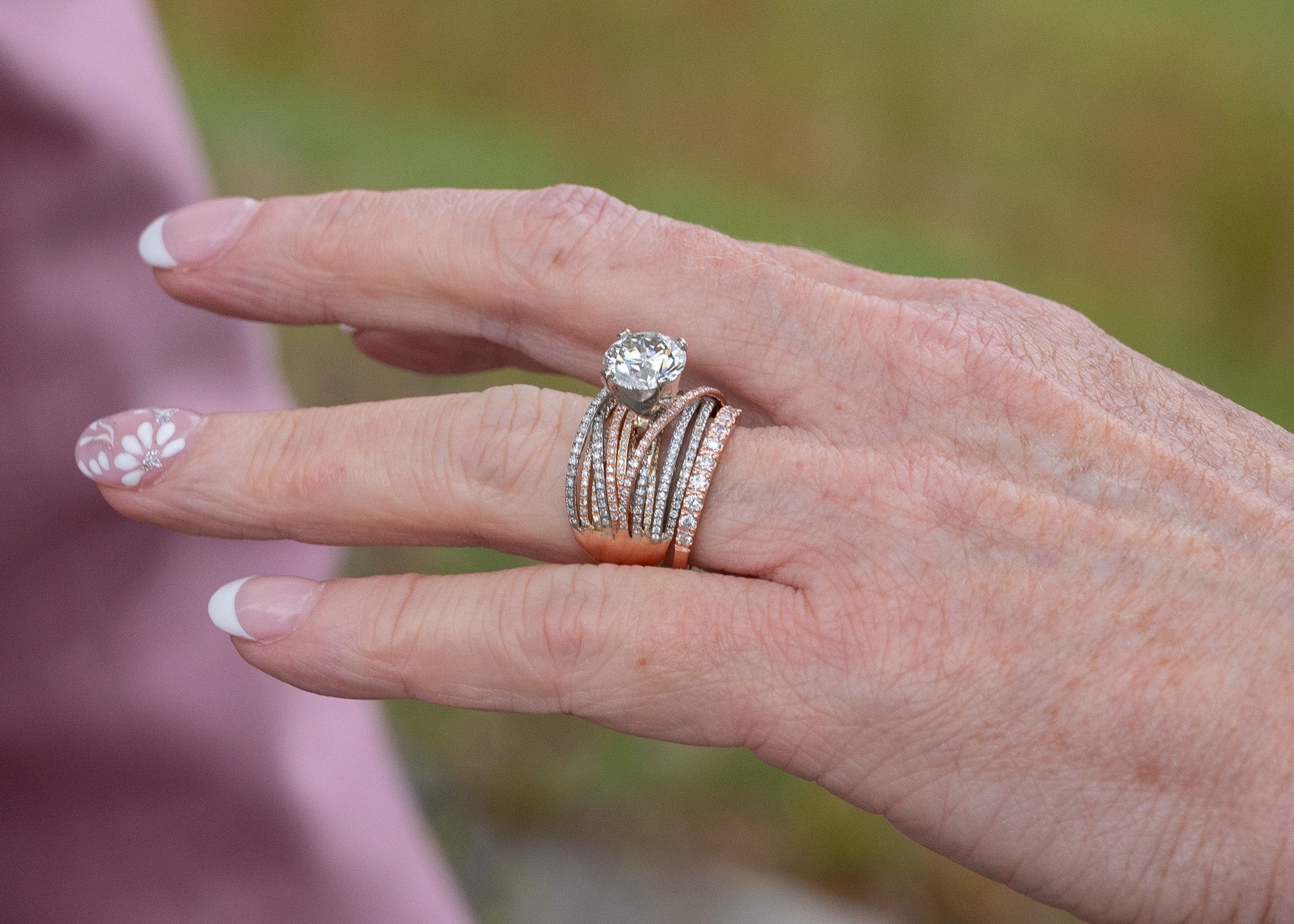 Close-up of hands showing wedding rings and jewelry.