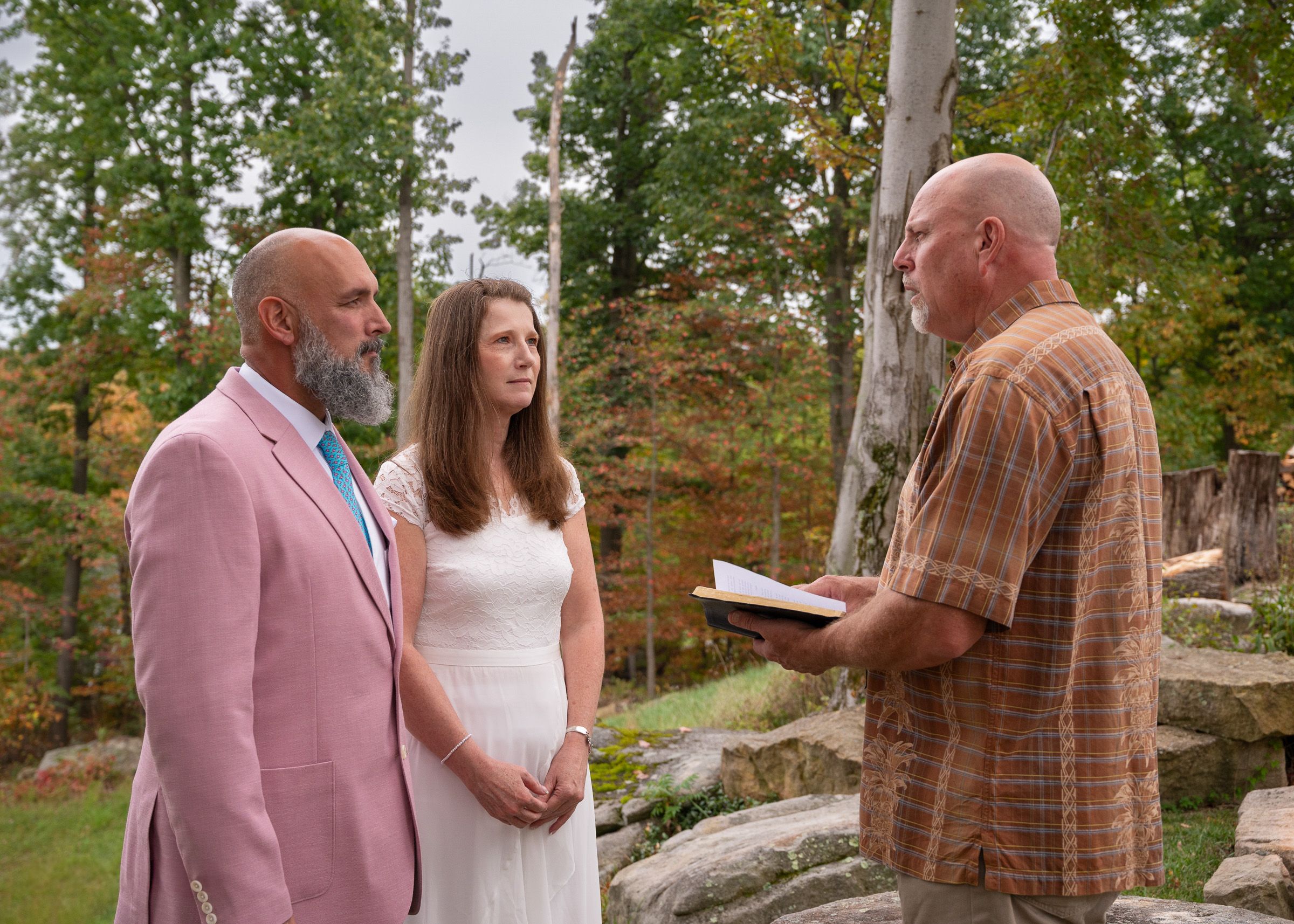 Wedding ceremony participants standing on rocky terrain surrounded by fall foliage.