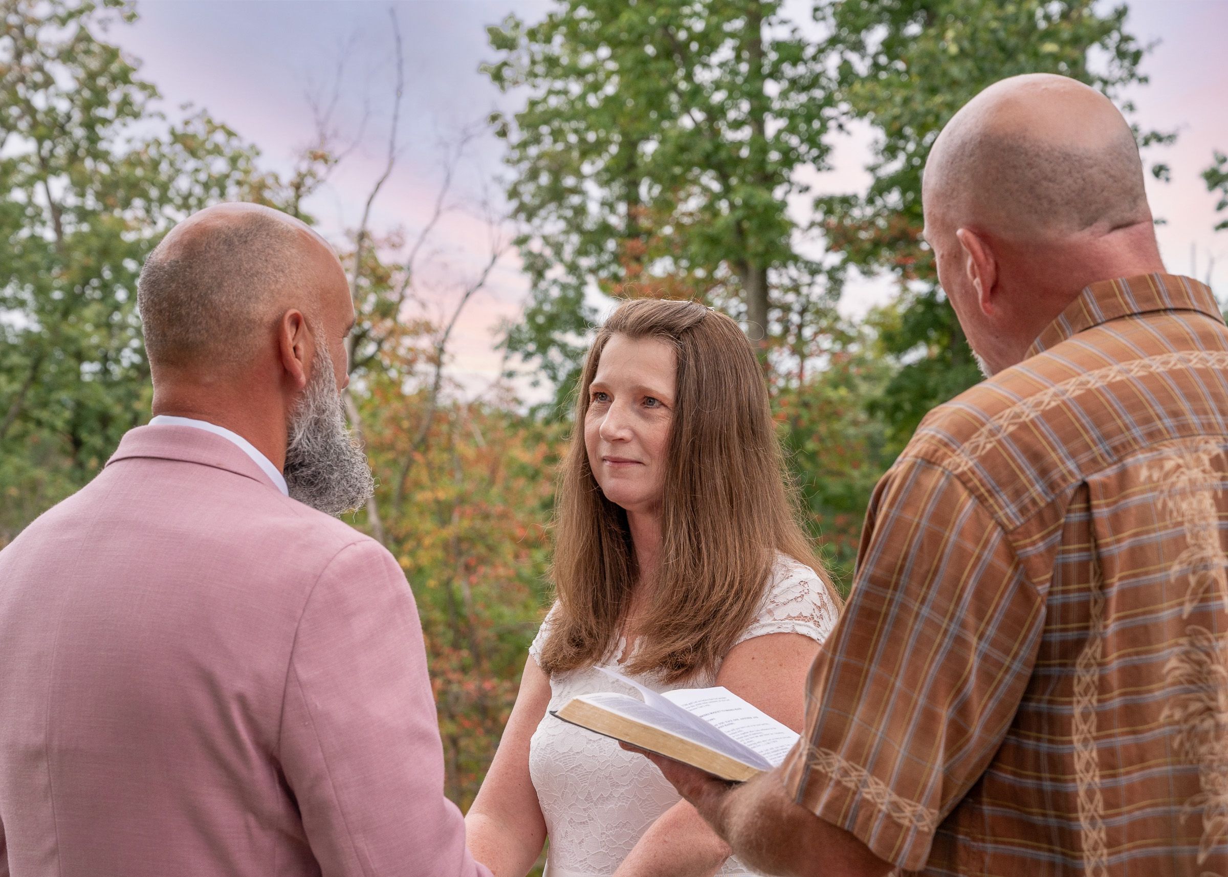 Intimate outdoor wedding ceremony with officiant and couple in natural setting.