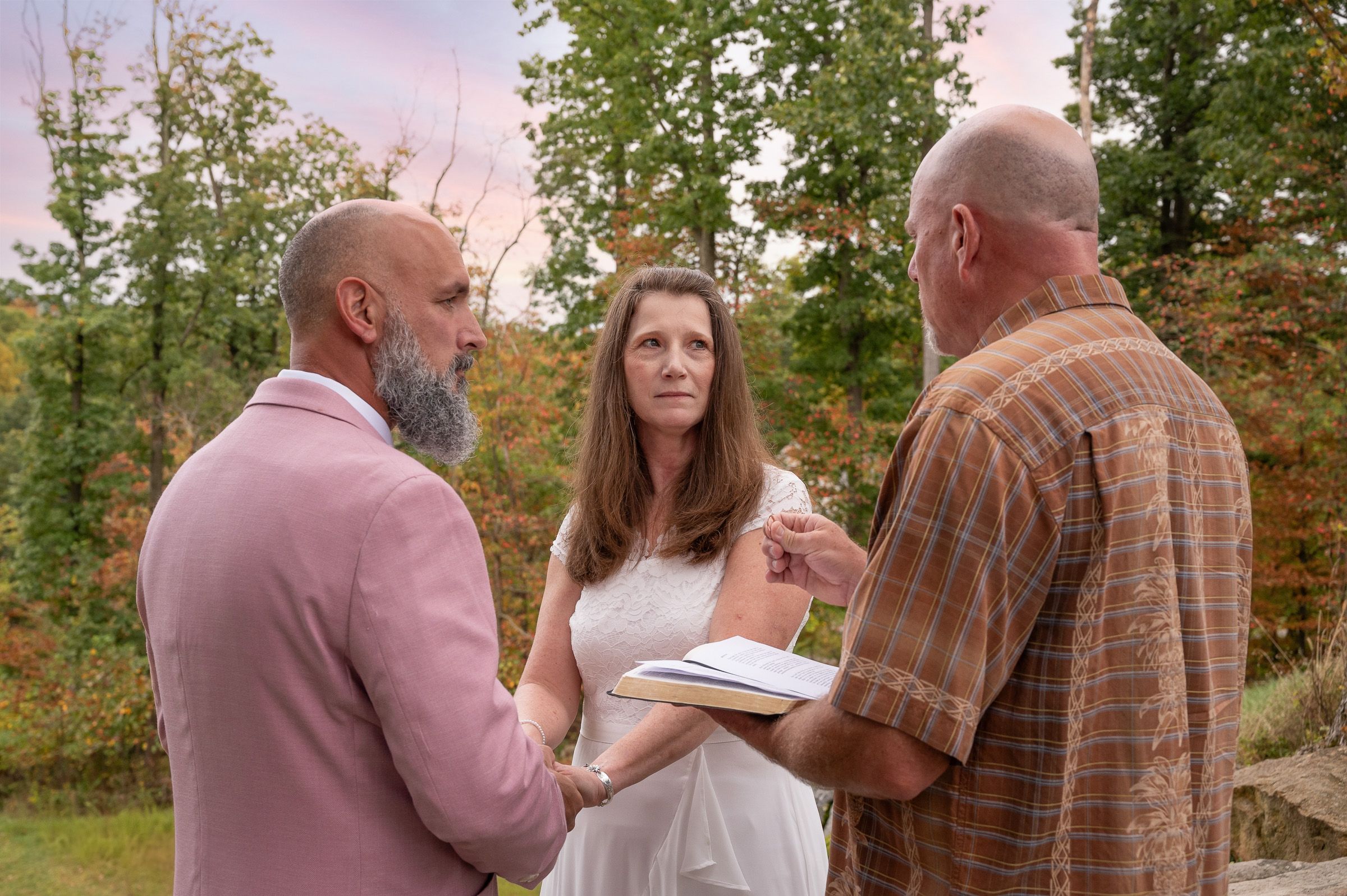 Wedding vows being exchanged in a serene outdoor setting with fall colors.