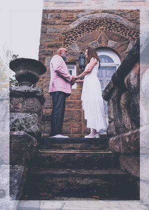 Wedding couple standing against rustic stone architecture.