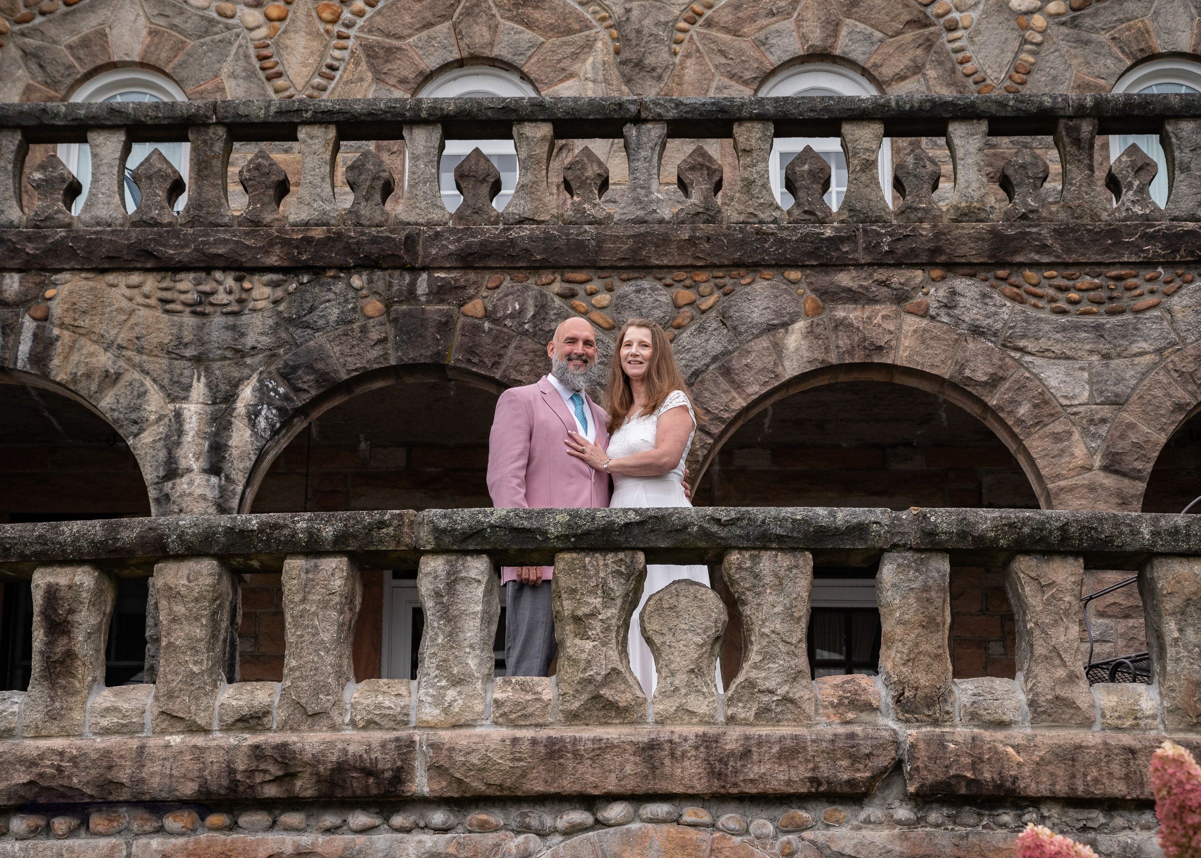 Wedding ceremony taking place under historic stone archways.