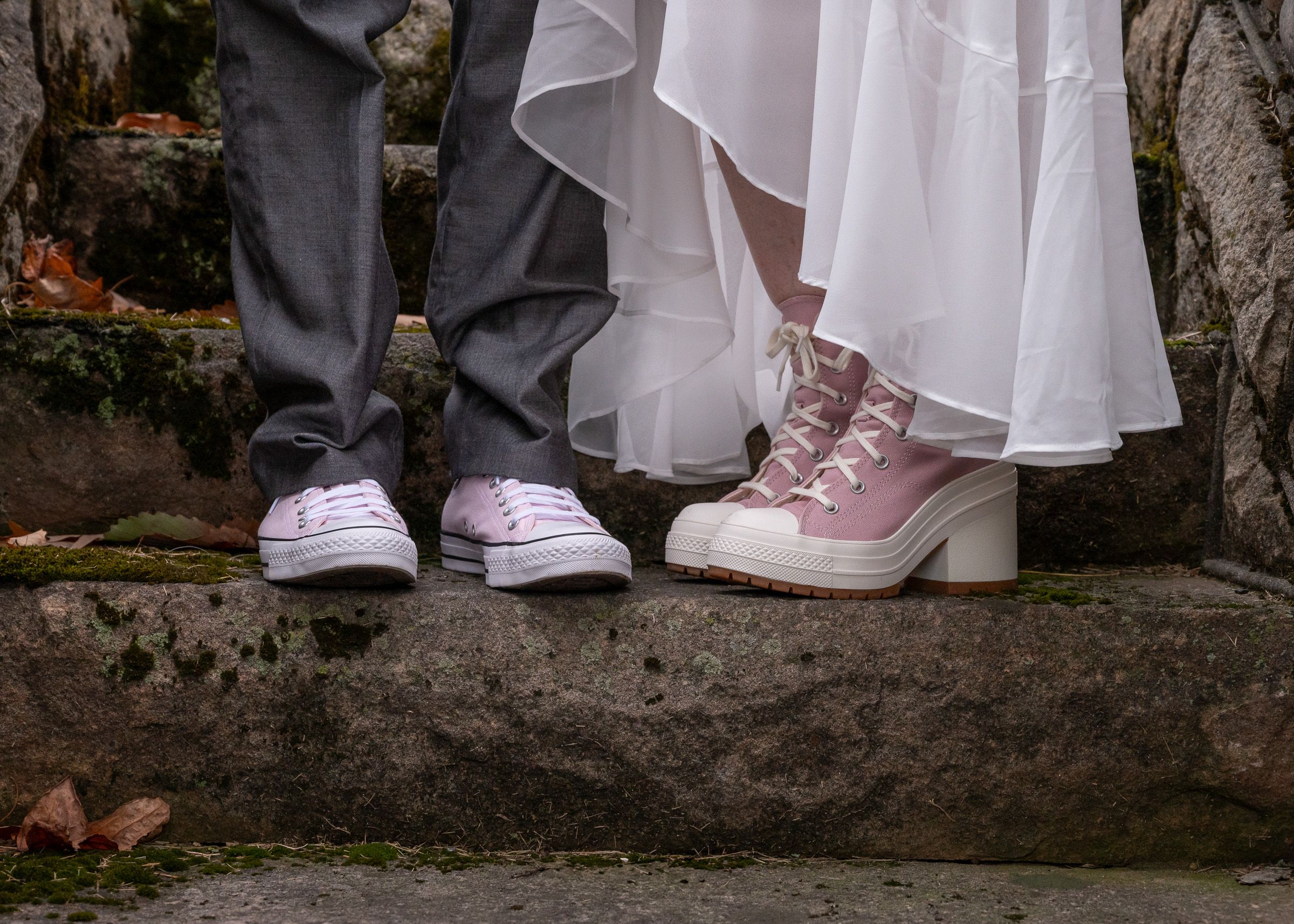 Sneakers lined up against an aged stone wall.