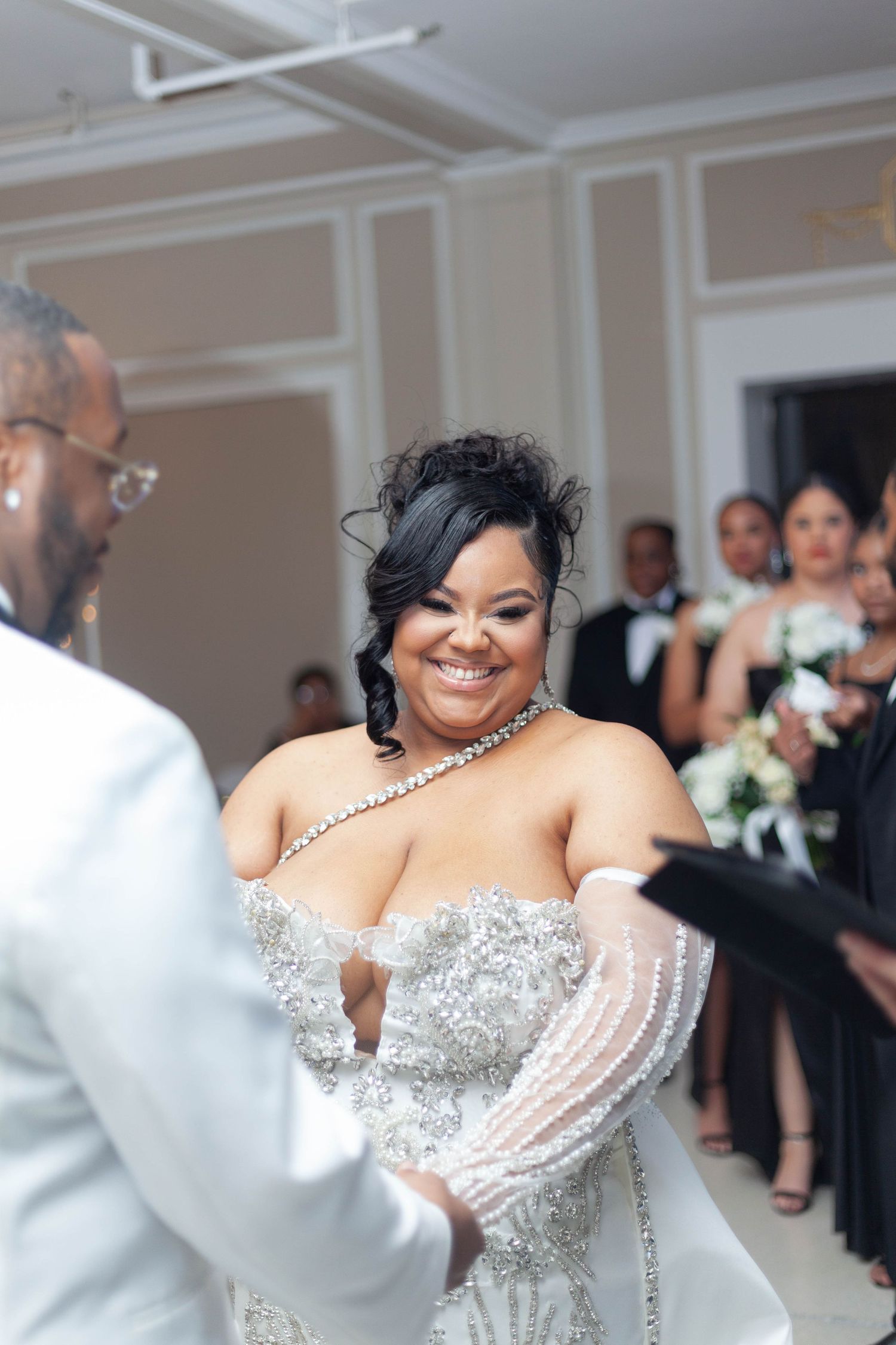 A bride in a sparkling white wedding gown with crystal embellishments dances during a wedding reception.