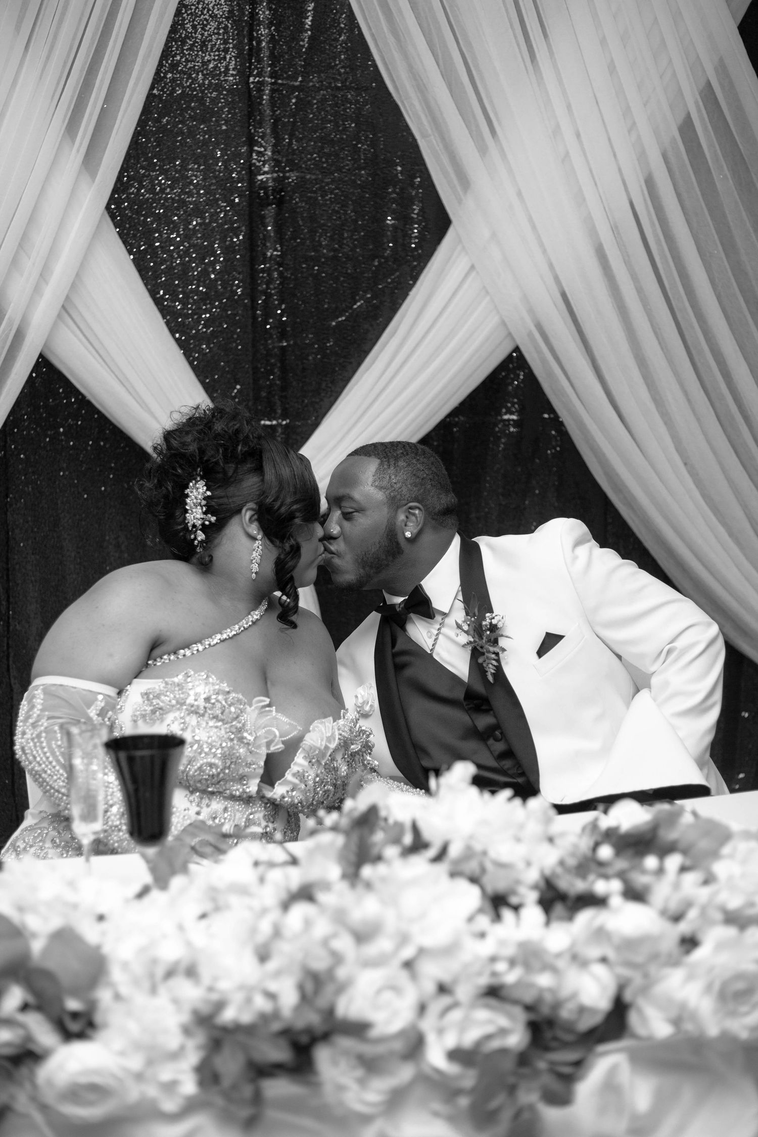 A romantic black and white photo series of a couple sharing tender kisses at their wedding reception.