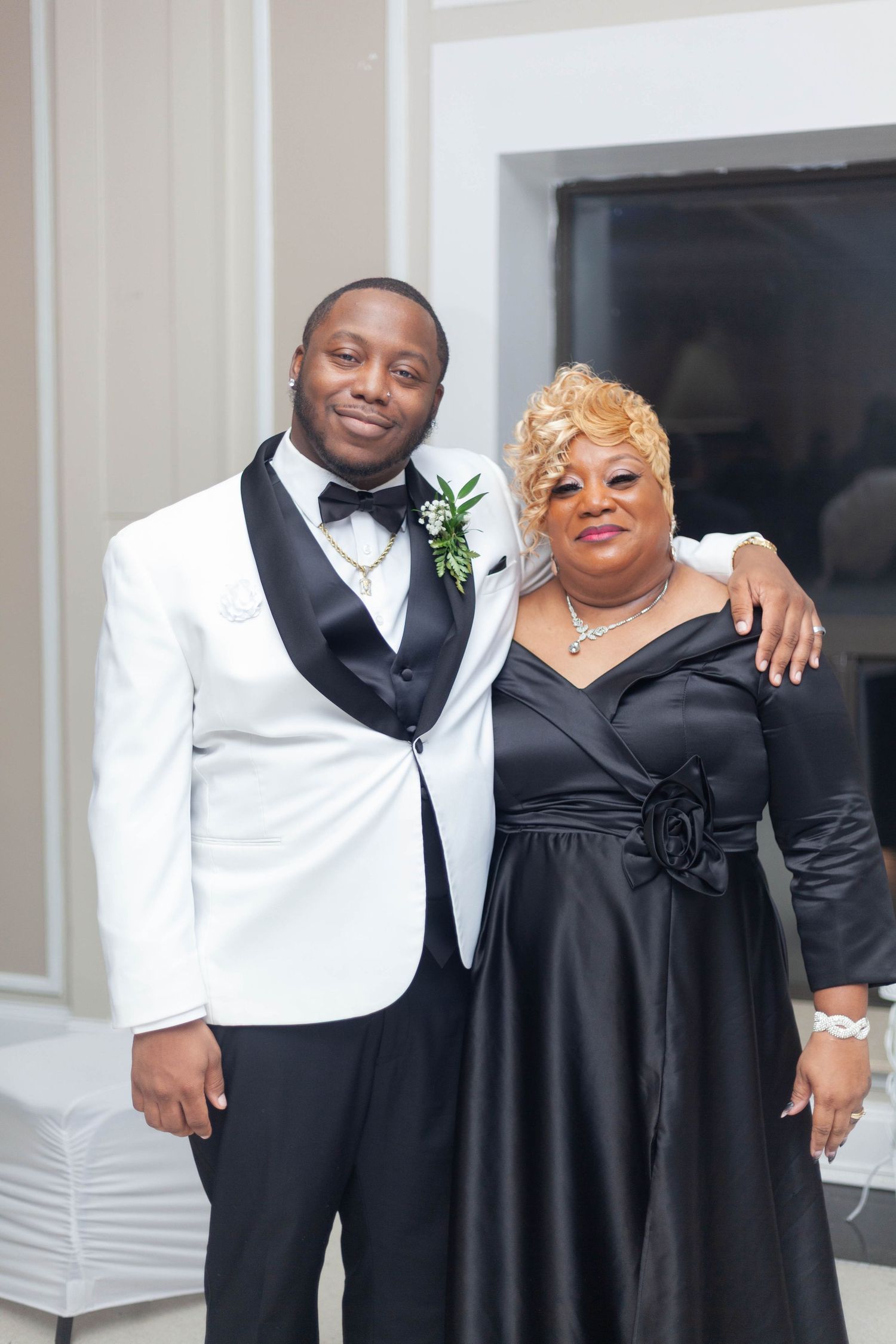 A couple in formal black and white attire pose together at an elegant event.