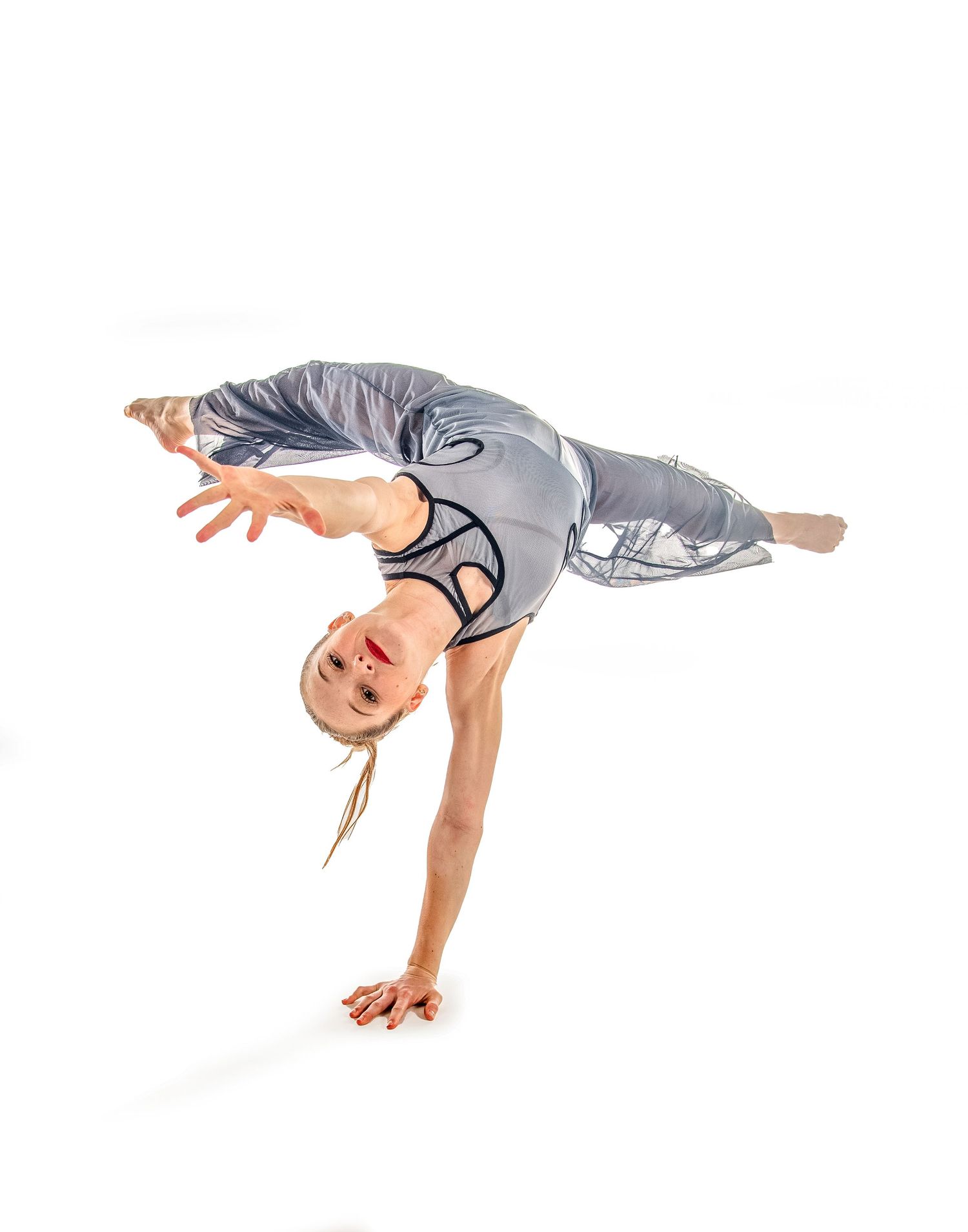 A dancer in beige clothing performs a series of graceful lunging movements against a dark background.