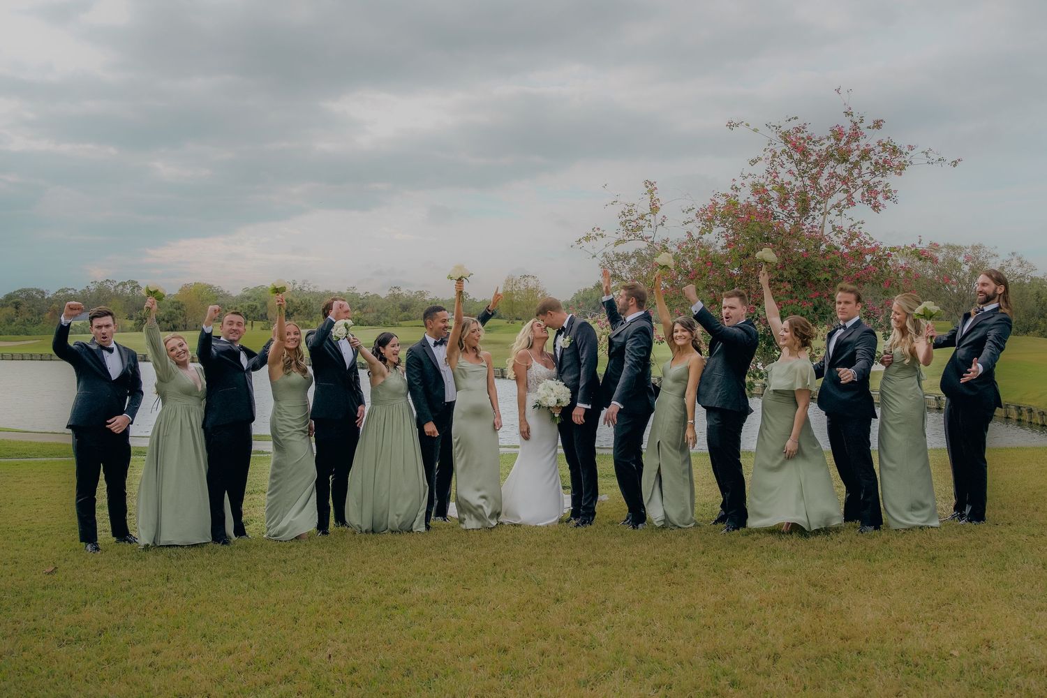 Wedding party poses together in a scenic outdoor field during golden hour.