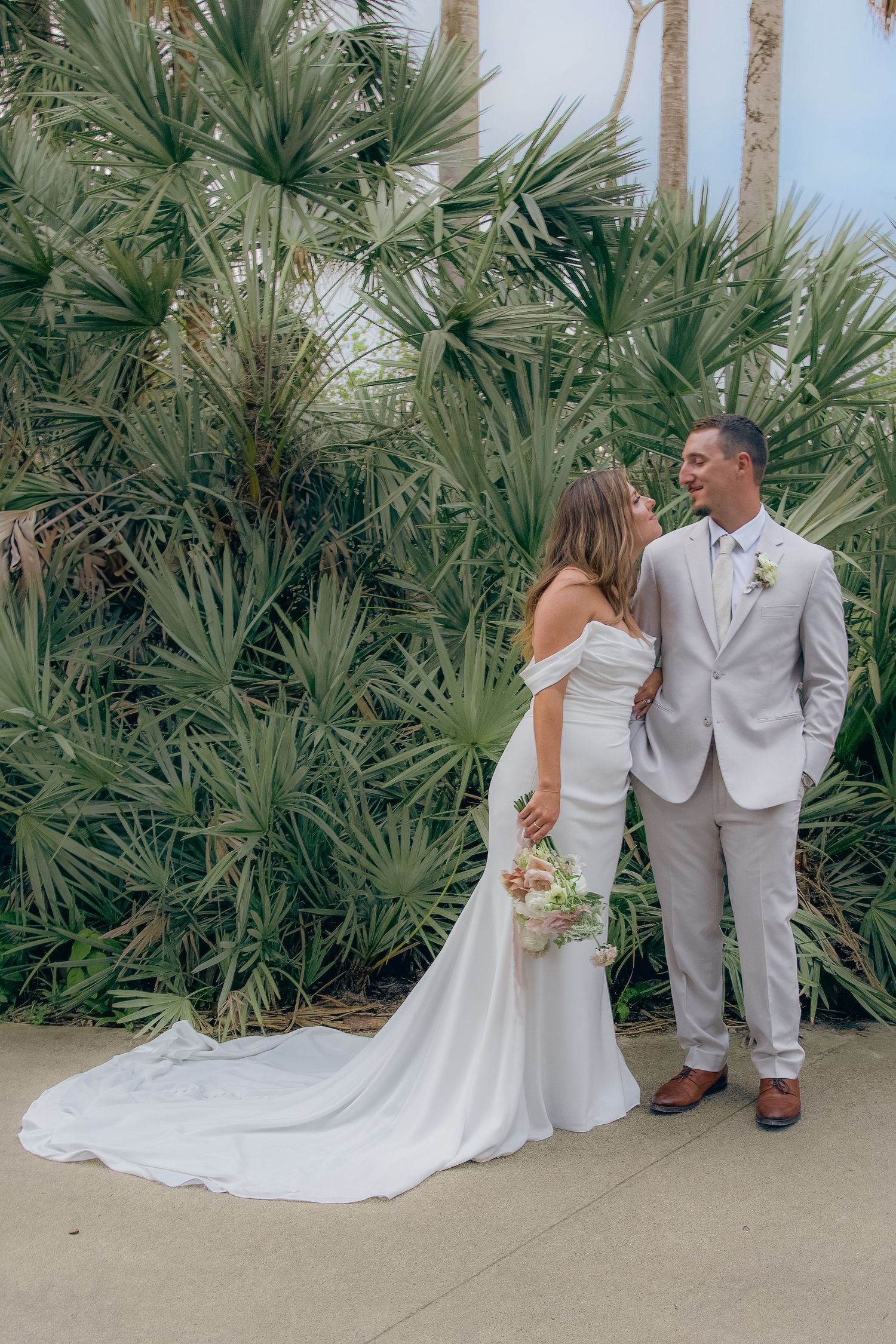 A wedding couple poses together against a backdrop of tropical palm trees in a series of romantic shots.