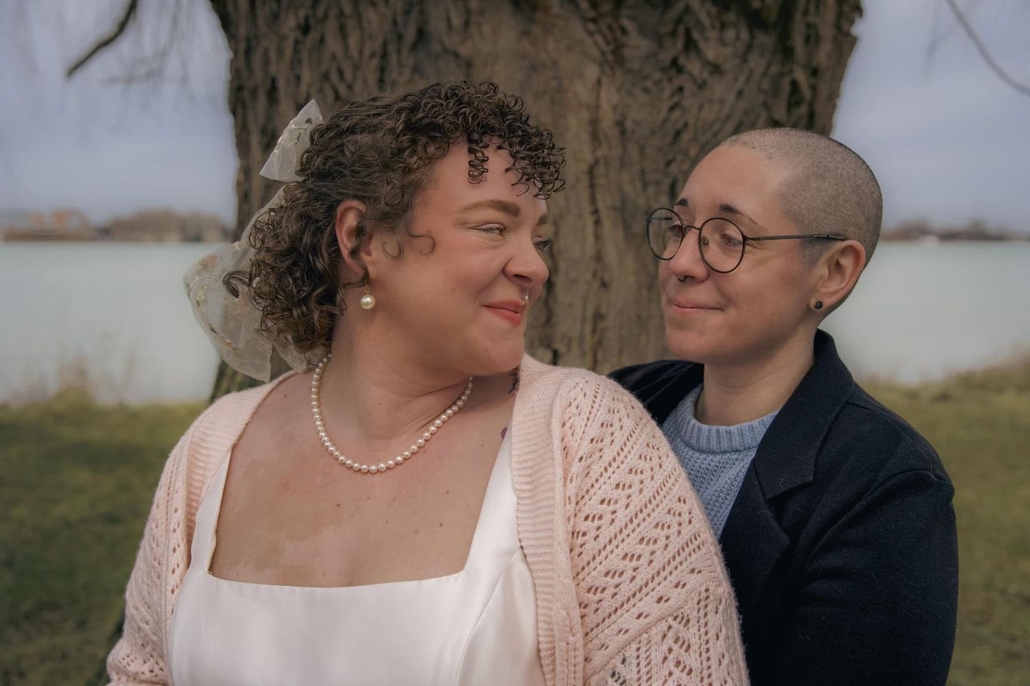 A loving couple shares a tender moment outdoors while sitting close together near a tree.