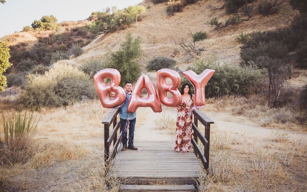 Multiple views of a wooden bench and red 'BABY' letters arranged on a dry grassy hillside during golden hour.
