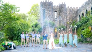 Wedding party celebrates with arms raised in front of a historic stone castle photos by Wollongong Wedding Photographer Serene Coleman
