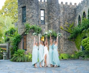 Wedding party celebrates with arms raised in front of a historic stone castle photos by Wollongong Wedding Photographer Serene Coleman