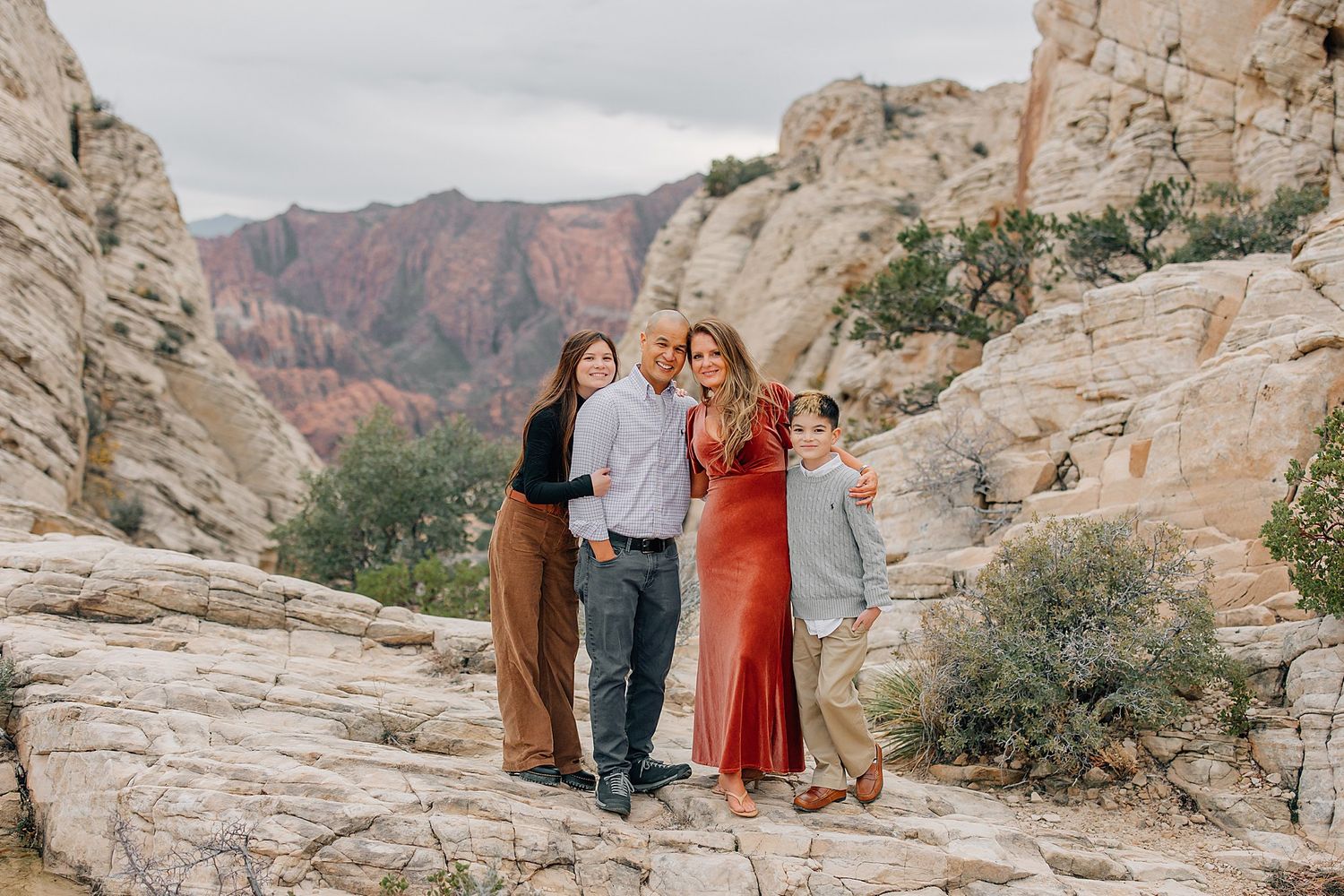 Group gathers on rugged desert cliff overlook with dramatic canyon landscape stretching into the distance.