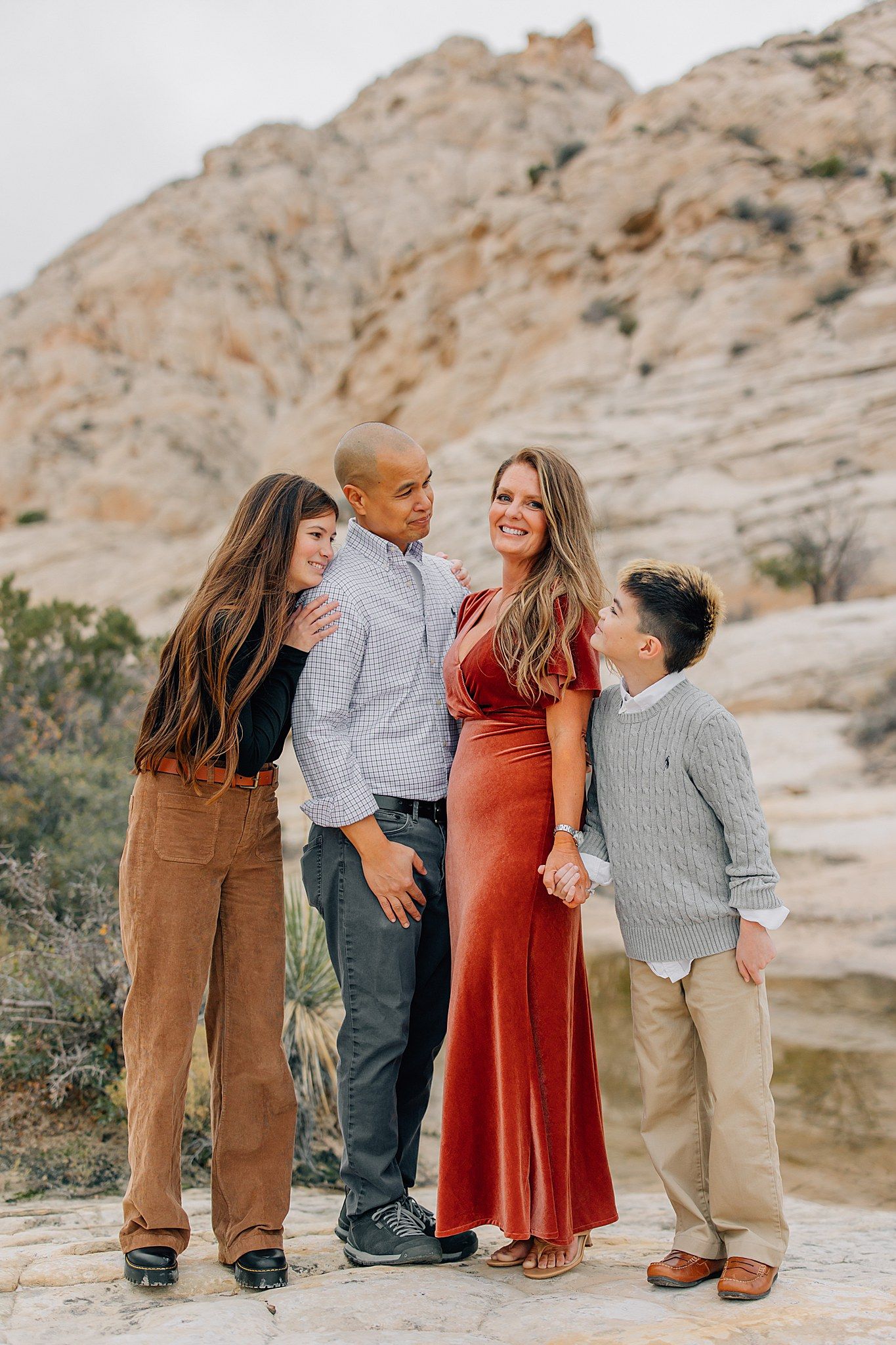A sweet family portrait session captured against a scenic desert landscape with natural rock formations.