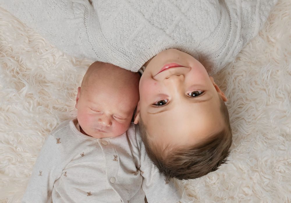 A series of five black and white photographs showing a baby lying on textured fabric in different poses.