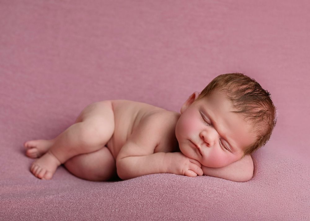 A sleeping newborn baby lies peacefully on soft pink fabric in a series of artistic portraits.