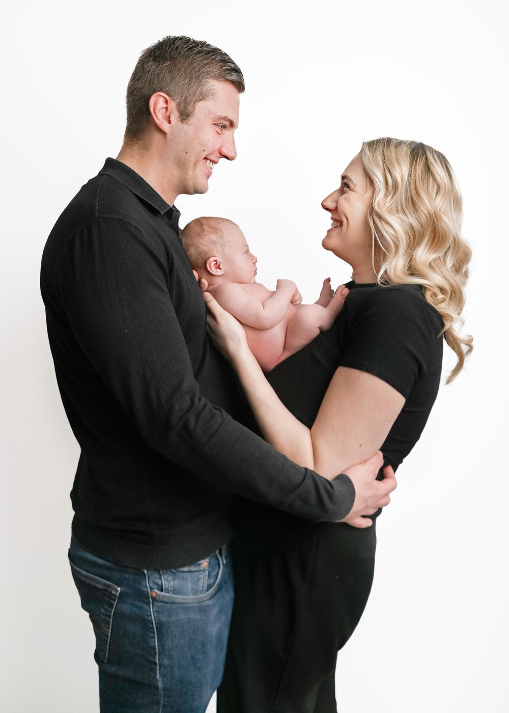 A couple in black clothing share playful laughing moments in a series of connected photos against a white backdrop.