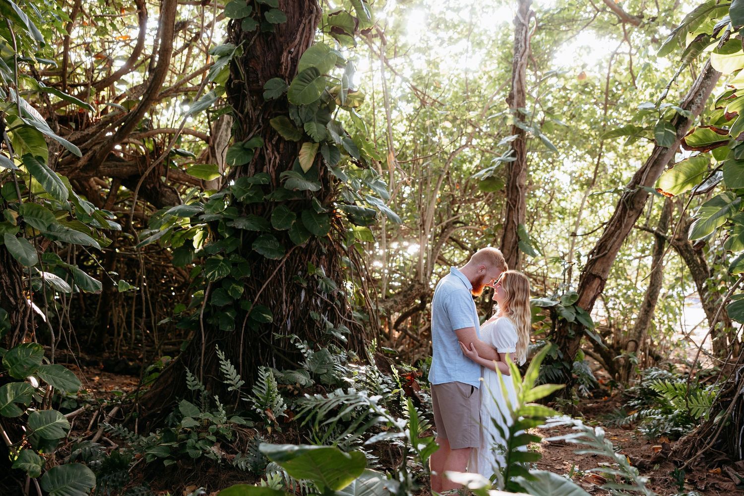 A couple embraces during a romantic outdoor photo session in a lush wooded forest setting.