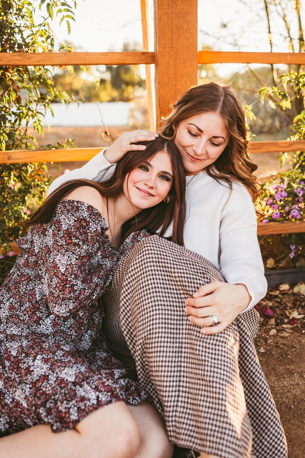 Two people share a tender embrace while sitting outdoors during golden hour sunset.