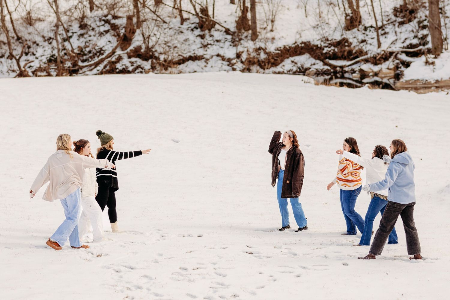 Group of friends laugh and play together in a snowy winter landscape outdoors.
