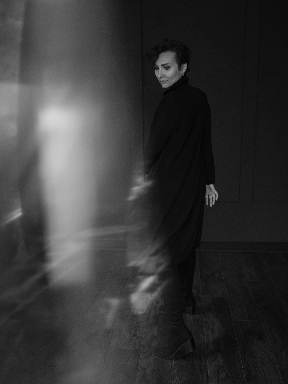 Artistic black and white portrait series showing a figure in dark clothing against a moody shadowed background.