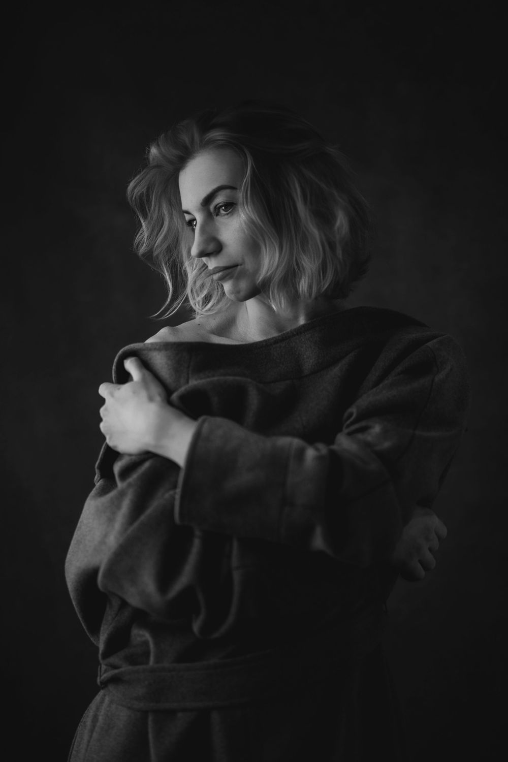 Artistic black and white photo sequence capturing moody poses of a person in dark clothing against a black background.