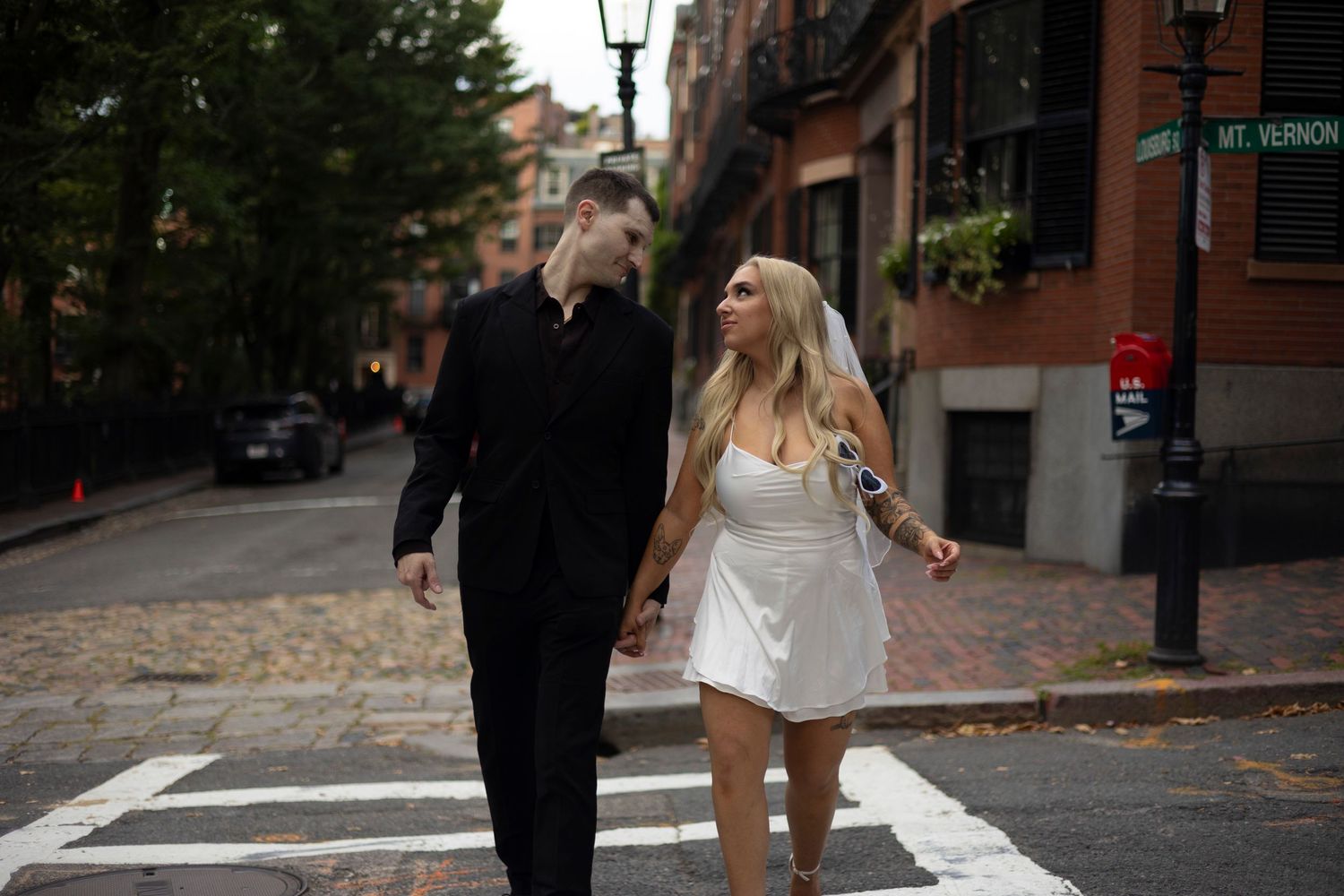 A couple walks together on a brick-lined street in Boston's historic Beacon Hill neighborhood during autumn.