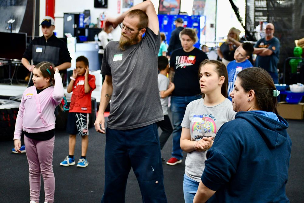 A group of people stretching and warming up together in a fitness class at a gym facility.