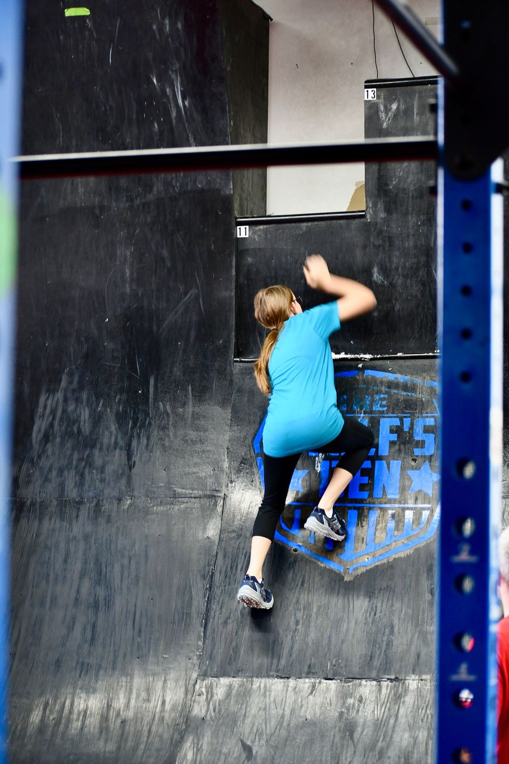 A sequence of photos showing a rock climber ascending a dark indoor climbing wall wearing blue athletic clothing.