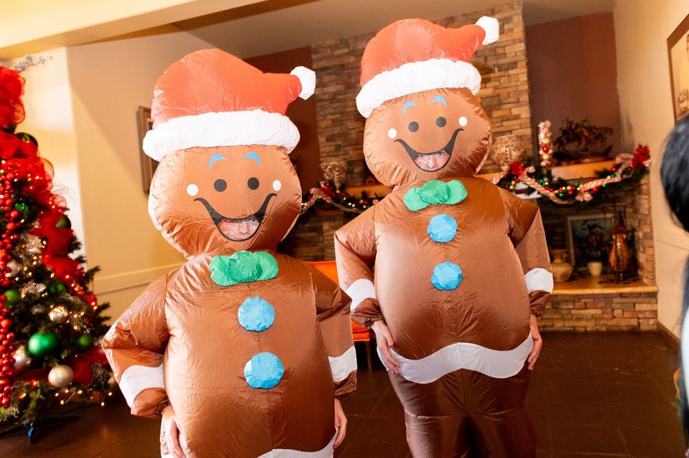 A row of gingerbread man decorations with Santa hats and blue buttons displayed in front of Christmas decor.